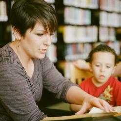 Adult reading with child in a library