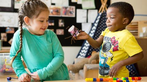 Preschool boy showing girl his craft project
