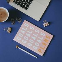 Notebook that says goals and a laptop.