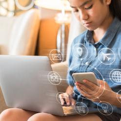 Girl looking at a computer and her smartphone