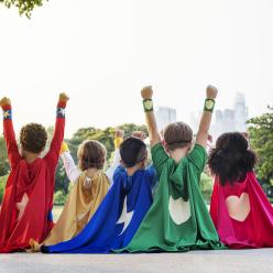 The backs of kids in superhero capes