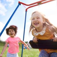 Two children smiling on the swings