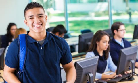 Man wearing backpack is smiling in computer lab