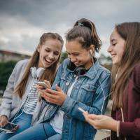 Three girls listening to music on their smartphones