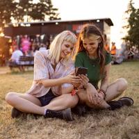 Two teen girls looking at a mobile phone and laughing