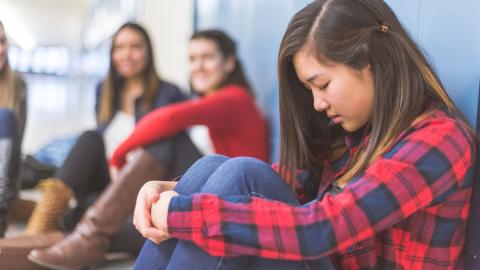 Upset girl sitting against lockers