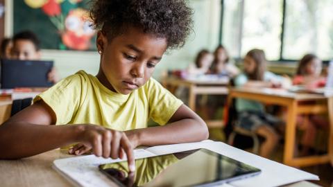 Young student using an iPad at their desk